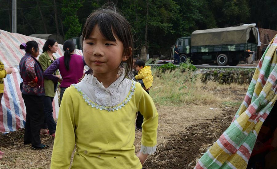 4月21日，住在簡易帳篷裡的高夢思。4月20日，蘆山縣龍門鄉，地震發生時9歲的高夢思在和4歲的弟弟在家，一塊木板砸在弟弟的頭上，高夢思一把抱起弟弟到了安全的地方，檢查后弟弟只是受了些輕傷。中新社發 張元 攝 