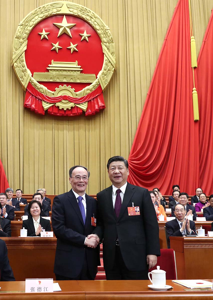 3月17日，十三屆全國人大一次會議在北京人民大會堂舉行第五次全體會議。習近平當選中華人民共和國主席、中華人民共和國中央軍事委員會主席。這是習近平在主席臺上同新當選的國家副主席王岐山握手。新華社記者 鞠鵬 攝